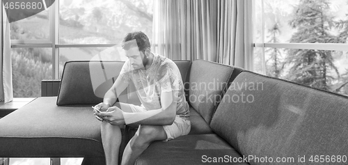 Image of young casual man using a mobile phone at home