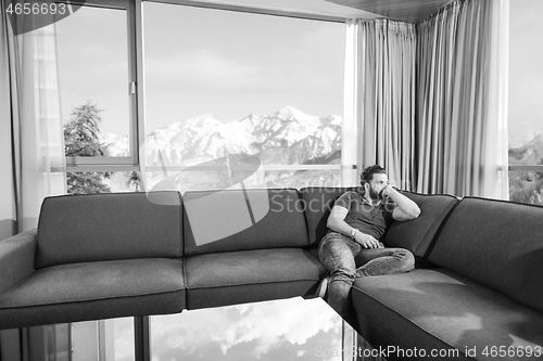 Image of young casual man using a mobile phone at home