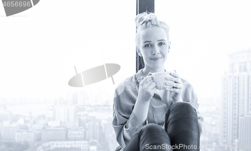 Image of woman drinking coffee and using laptop at home