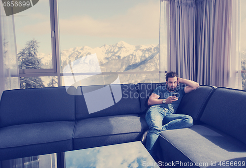 Image of young casual man using a mobile phone at home