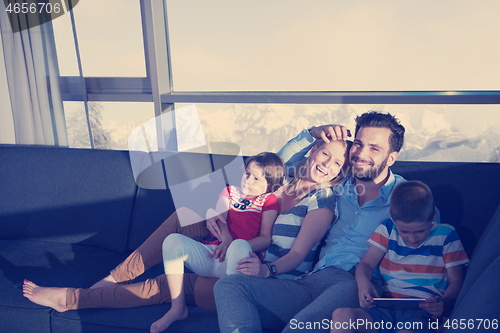 Image of happy young couple spending time with kids at home