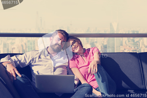 Image of couple relaxing at  home using laptop computers