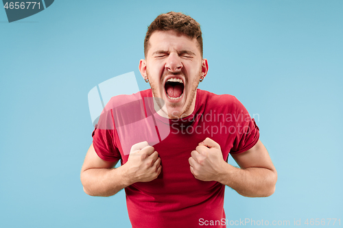 Image of The young emotional angry man screaming on blue studio background