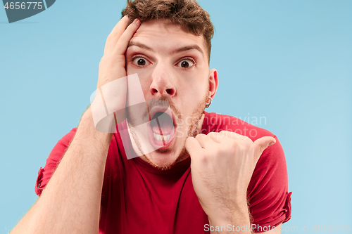 Image of The young attractive man looking suprised isolated on blue