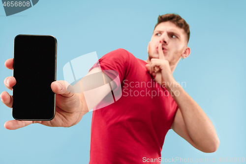 Image of Portrait of the scared man with phone on blue