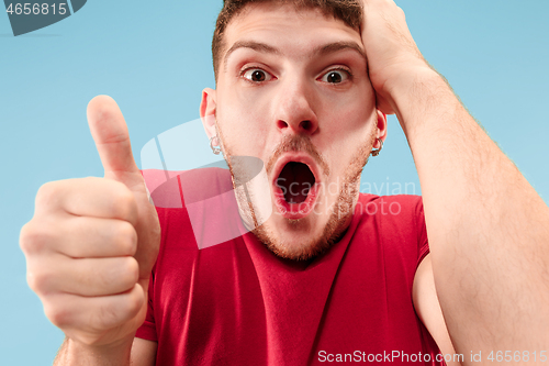 Image of The young attractive man looking suprised isolated on blue