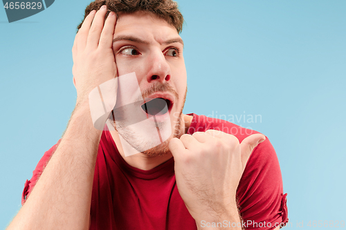 Image of The young attractive man looking suprised isolated on blue