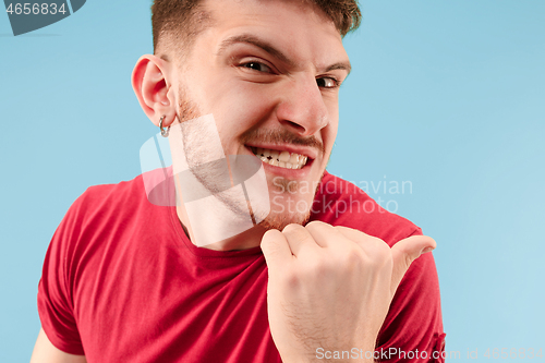 Image of The young man whispering a secret behind her hand over blue background