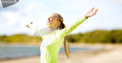 Image of happy woman in sports clothes on beach