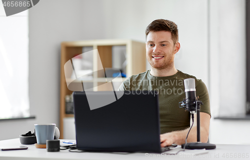 Image of man with laptop and microphone at home office