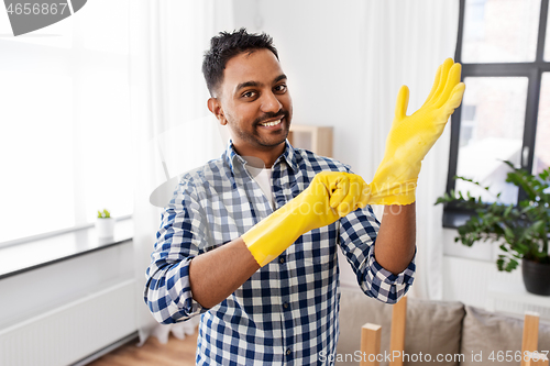 Image of indian man putting protective rubber gloves on