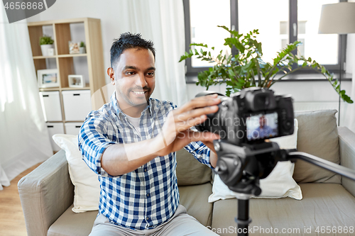 Image of indian male video blogger adjusting camera at home