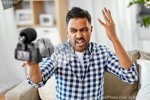 Image of male video blogger with camera blogging at home