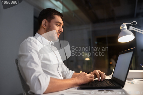 Image of businessman with laptop working at night office