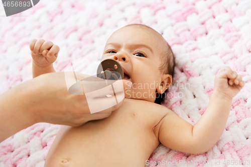 Image of mother\'s hand giving pacifier to baby daughter