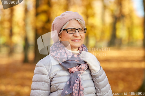 Image of portrait of happy senior woman at autumn park