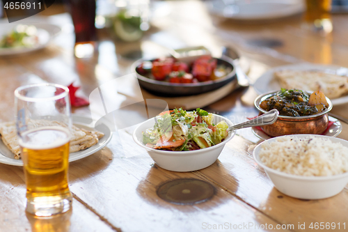 Image of salad with other food on indian restaurant table