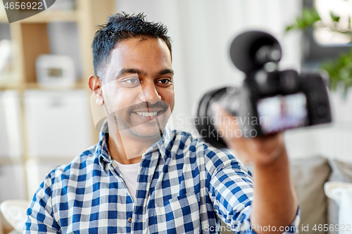 Image of male video blogger with camera blogging at home