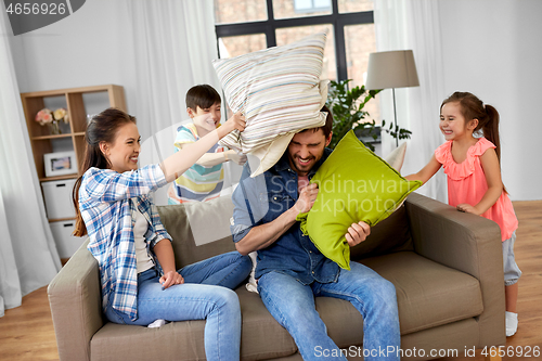 Image of happy family having pillow fight at home