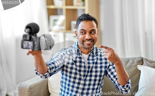 Image of male video blogger with camera blogging at home