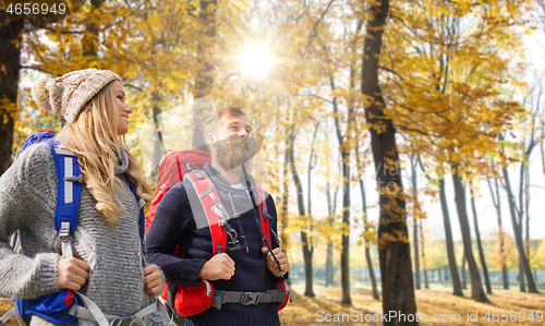 Image of smiling couple with backpacks hiking in autumn