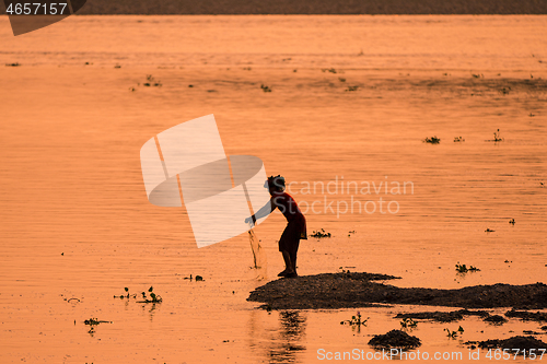 Image of Asian Woman fishing in the river, silhouette at sunset