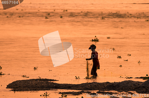 Image of Asian Woman fishing in the river, silhouette at sunset