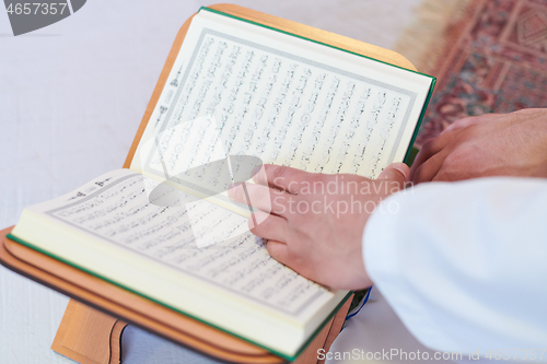 Image of arabian muslim man reading Quran at home