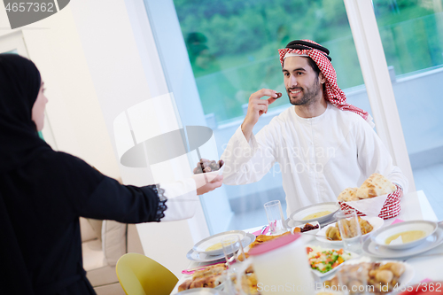 Image of Muslim family having Iftar dinner eating dates to break feast