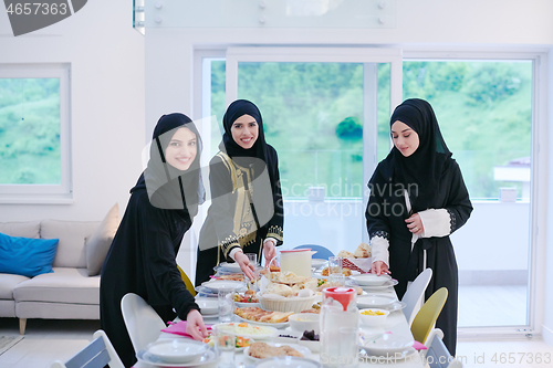 Image of young muslim girls serving food on the table for iftar dinner