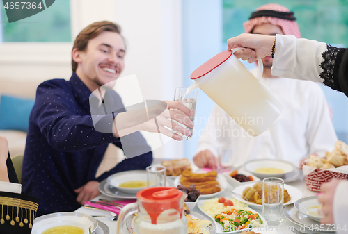 Image of Muslim family having Iftar dinner drinking water to break feast