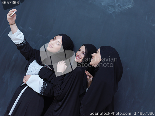 Image of muslim women taking selfie picture in front of black chalkboard