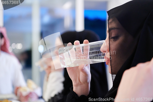 Image of Muslim family having Iftar dinner drinking water to break feast