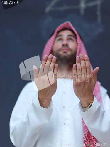 Image of arabian man making traditional prayer to God, keeps hands in pra