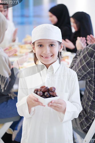 Image of little muslim boy holding a plate full of sweet dates