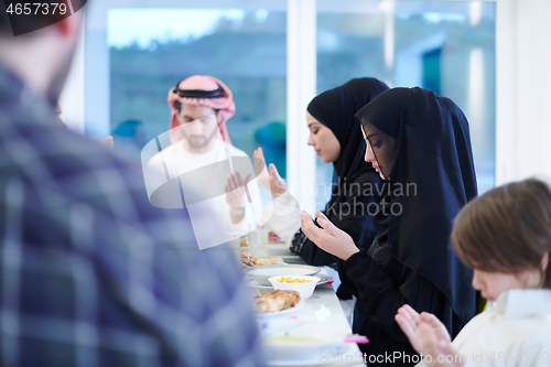 Image of traditional muslim family praying before iftar dinner