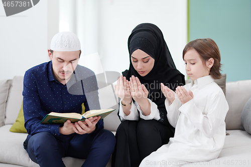 Image of muslim family reading Quran and praying at home