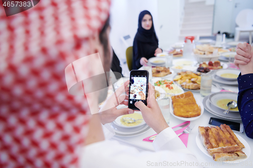 Image of Muslim family having Iftar dinner taking pictures with mobile ph