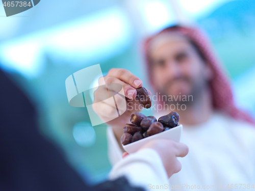 Image of Muslim family having Iftar dinner eating dates to break feast