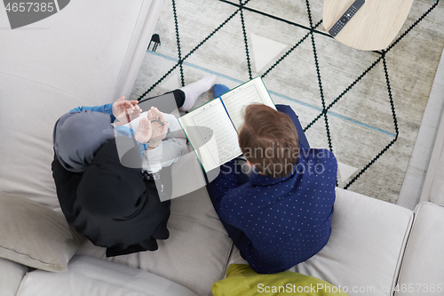 Image of muslim family reading Quran and praying at home top view