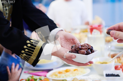 Image of Muslim family having Iftar dinner eating dates to break feast