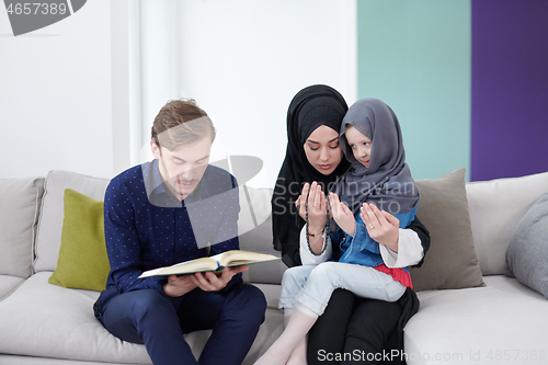 Image of muslim family reading Quran and praying at home