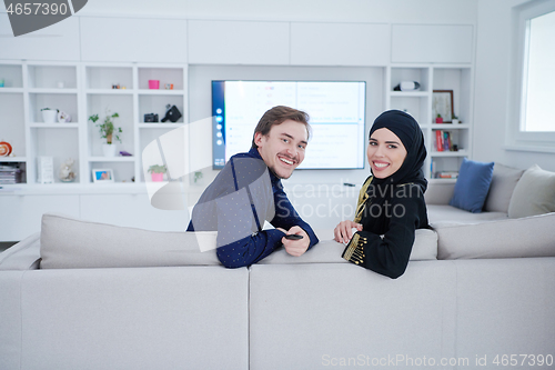 Image of young muslim couple watching TV together