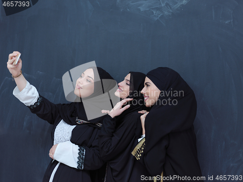 Image of muslim women taking selfie picture in front of black chalkboard