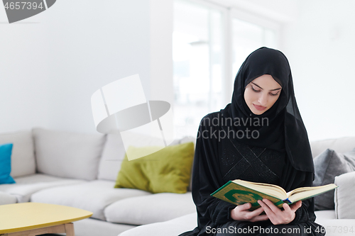 Image of young muslim woman reading Quran at home