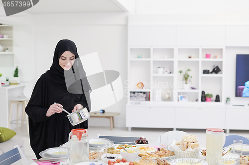 Image of young muslim girl serving food on the table for iftar dinner