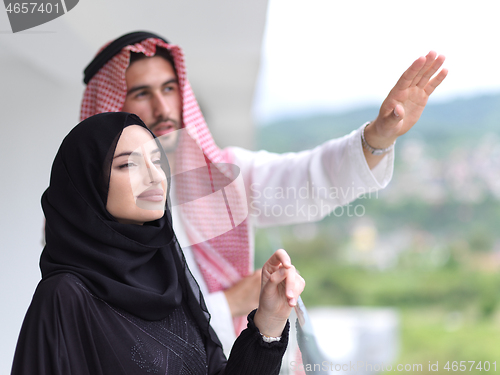 Image of portrait of beautiful arabian couple standing on balcony