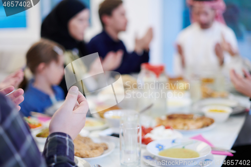 Image of traditional muslim family praying before iftar dinner