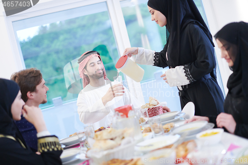 Image of Muslim family having Iftar dinner drinking water to break feast