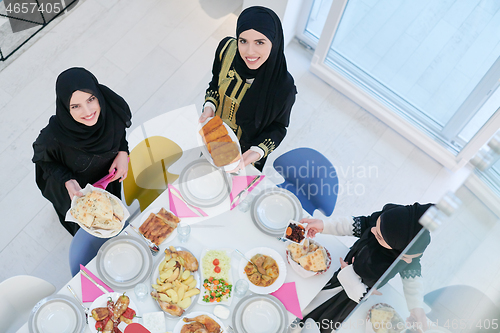 Image of young muslim girls serving food on the table for iftar dinner to